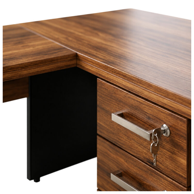 Detalhe do encontro dos tampos da mesa em L, com gaveteiro amadeirado, puxadores prateados e chave.