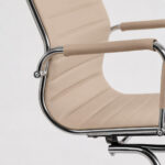 Close da Cadeira Charles Eames mostrando encaixe entre assento, braço revestido e estrutura cromada.