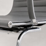 Detalhe estrutural da Cadeira Charles Eames cinza mostrando junção entre encosto, braço e estrutura cromada.