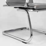 Detalhe da Cadeira Charles Eames cinza mostrando corino cinza e acabamento metálico cromado em destaque.