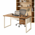 Mesa de escritório pé quadro com duas gavetas, notebook e cadeira de tela, com estante amadeirada ao fundo.