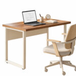 Mesa com tampo amadeirado e estrutura metálica clara, acompanhada de notebook, relógio e cadeira giratória de braços claros.