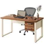 Mesa com gavetas e cadeira de tela em composição Mesa com duas gavetas, notebook, livros e vaso, acompanhada de cadeira de tela cinza com base de rodízios.