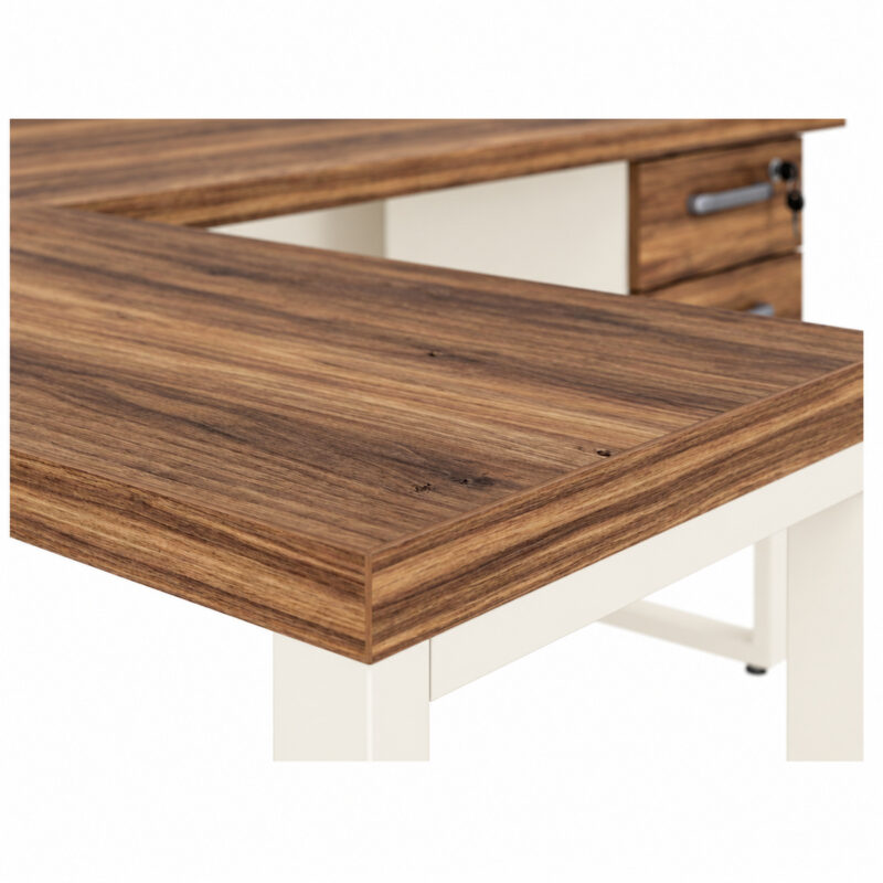 Mesa em L pé quadro com aproximação do tampo auxiliar amadeirado, borda engrossada e gaveteiro ao fundo.