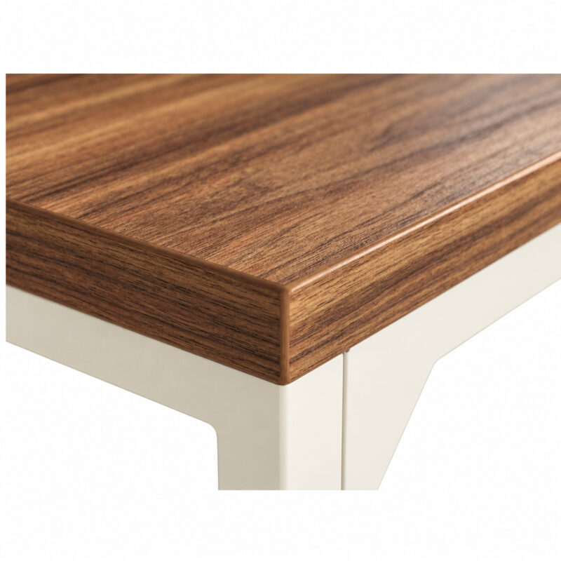 Mesa em L pé quadro com detalhe do canto do tampo amadeirado e da estrutura metálica clara sob a borda.