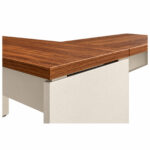 Mesa em L com detalhe da borda amadeirada e dos distanciadores entre o tampo e o pé em painel Champanhe.