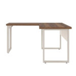 Mesa em L — vista pela extremidade do tampo Mesa em L vista pela extremidade, com pé metálico em quadro em primeiro plano e extensão amadeirada ao fundo.