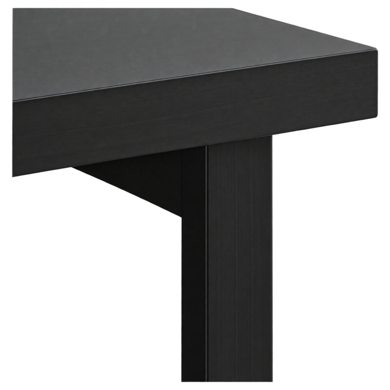 Detalhe da mesa preta mostrando a borda do tampo, o encontro com o apoio vertical e parte do painel inferior.