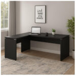 Mesa em L preta para home office em Goiânia Mesa preta em L com notebook e acessórios em home office com janela, plantas, quadro decorativo e tapete claro.