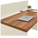Detalhe do tampo amadeirado com notebook fechado e cabo junto ao módulo central, abaixo da divisória Champanhe.