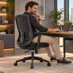 Cadeira giratória em tela preta — em uso na mesa de trabalho Pessoa sentada na cadeira preta com encosto em tela diante de uma mesa de trabalho.